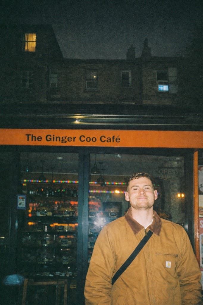 Alistair Hughes portrait outside The Ginger Coo Café at night